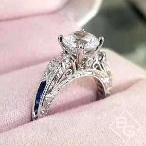Kirk Kara White Gold "Charlotte" Three Stone Blue Sapphire Diamond Engagement Ring Angled Side View in Box