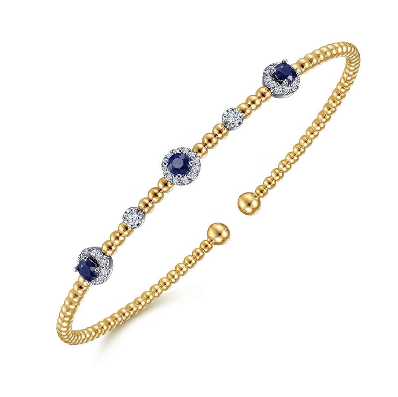 Angled view of the white and yellow gold Bujukan sapphire bangle showing the beaded band
