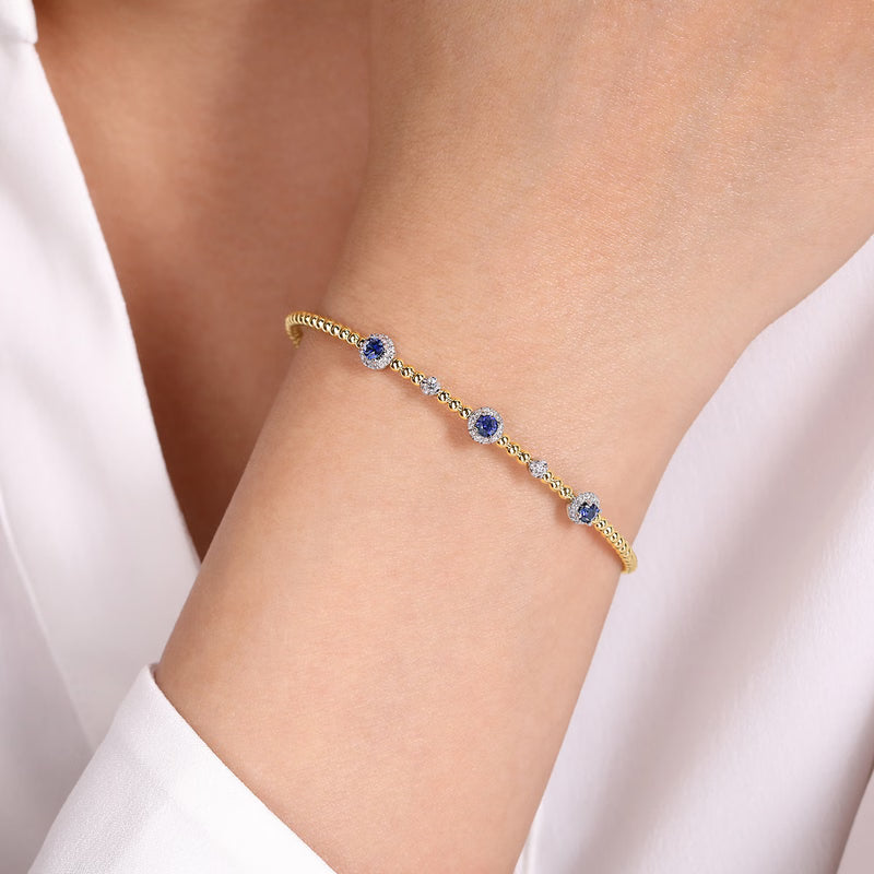 Two-tone yellow gold Bujukan sapphire bangle worn on the wrist