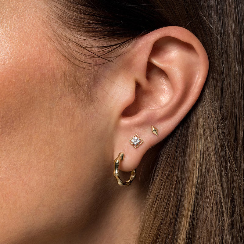Gabriel & Co. EG14414 flower diamond stud earring worn with a gold huggie hoop in a stacked ear