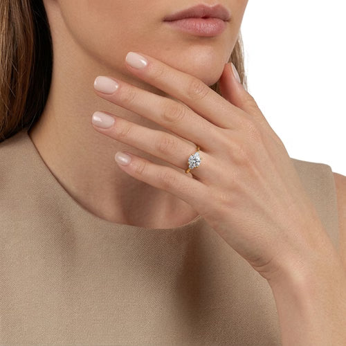 Gabriel & Co. Madison round three stone Lotus engagement ring in 14K yellow gold in 14K yellow gold with 0.30 ct side diamonds at Ben Garelick Jewelers On Hand