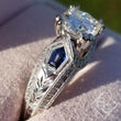 Load image into Gallery viewer, Kirk Kara White Gold &quot;Charlotte&quot; Kite Cut Blue Sapphire Diamond Engagement Ring Close Up Angled Side View In Box
