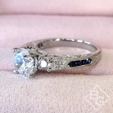 Load image into Gallery viewer, Kirk Kara White Gold &quot;Charlotte&quot; Three Stone Blue Sapphire Diamond Engagement Ring Angled Side View on Box
